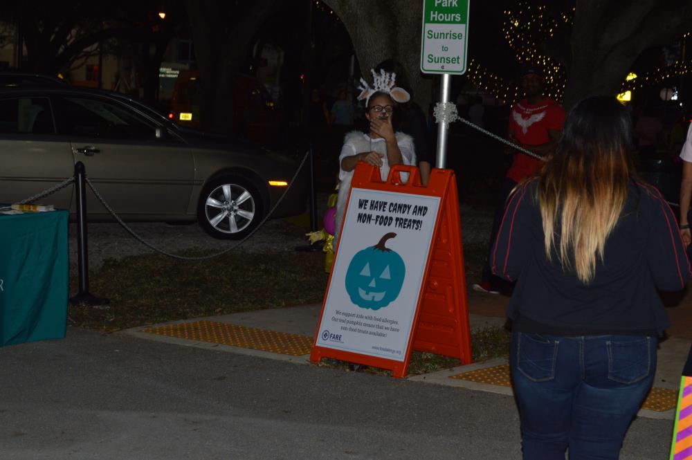 Person in lamb costume stands next to sign with text 